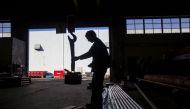 A sawyer uses a giant magnet to move a cut of machine grade steel at the Pacific Machinery & Tool Steel Company on March 6, 2018 in Portland, Oregon.  Natalie Behring/AFP
