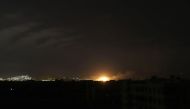 A picture taken late on March 10, 2018, shows an explosion, from a Syrian government air strike, illuminating the town of Arbin in the rebel-held enclave of Eastern Ghouta. AFP / AMER ALMOHIBANY
