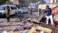 (FILES) In this file photo taken on March 6, 2018, police commandos patrol next to debris from a damaged shop in the central district of Kandy, after a state of emergency was declared. AFP