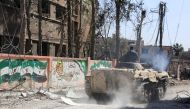  A member of the Syrian government forces rides on top of an infantry-fighting vehicle (IFV) past a mural of the flag of the Syrian opposition and writing supporting Faylaq al-Rahman (Rahman Legion), in the town of Jisreen in the southern Eastern Ghouta, 