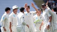 Trent Boult of New Zealand (C) celebrates a wicket during the first day of the day-night Test cricket match between New Zealand and England at Eden Park in Auckland on March 22, 2018. / AFP / Fiona Goodall