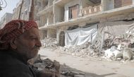 A Syrian man looks at a street and destoyed buildings following air strikes on March 25, 2018, in Douma, in Eastern Ghouta on the outskirts of the capital Damascus. AFP / HAMZA AL-AJWEH
