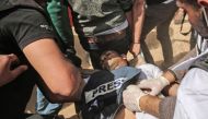 Demonstrators assist an injured Palestinian journalist Yasser Murtaja during clashes with Israeli security forces following a protest near the border with Israel, east of Khan Yunis, in the southern Gaza Strip, on April 6, 2018. AFP / SAID KHATIB