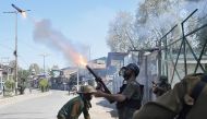 An Indian policeman fires a tear smoke shell towards protesters during the funeral of Mussavir Ahmed Wani, a suspected militant, who according to local media reports was killed in a gunbattle with Indian security forces on Friday, in south Kashmir's Pulwa