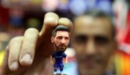 A sports shop keeper holds a figurine of Argentine football player Lionel Messi at a shop in Kuwait City on April 11, 2018, as Spain’s Real Madrid and Italy’s Juventus prepare to play for second leg of Europe Champions league quarter finals. AFP / Yasser 