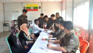 This handout photograph released by Myanmar News Agency on April 15, 2018 and taken April 14, 2018, Myanmar immigration official hands over identification document to an unidentified Rohingya woman belonging to the five member Rohingya family at Taungpyol