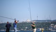 People are fishing on bosphorus river as new built Camlica mosque is seen in the backround on April 26, 2018 in Istanbul. AFP / OZAN KOSE
