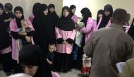 A picture taken on April 29, 2018 in the Iraqi capital Baghdad's Central Criminal Court shows Russian women who have been sentenced to life in prison on grounds of joining the Islamic State (IS) group standing with children in a hallway. Iraq sentenced 19