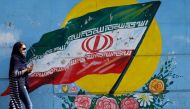 An Iranian woman walks past a mural of the Iranian flag in the capital, Tehran on October 14, 2017. (AFP) 