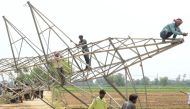 Indian workers remove a damaged electrical transmission tower which collapsed in a storm on May 12 in Ibban Kallan village on the outskirts of Amritsar on May 13, 2018. / AFP / NARINDER NANU