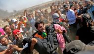 Palestinians carry a demonstrator injured during clashes with Israeli forces near the border between the Gaza strip and Israel east of Gaza City on May 14, 2018, as Palestinians protest over the inauguration of the US embassy following its controversial m