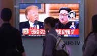 People walk past a television news screen showing North Korean leader Kim Jong Un (R) and US President Donald Trump (L) at a railway station in Seoul on May 16, 2018. AFP / Jung Yeon-je