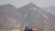 North Korean farmers work in a field as a section of the Great Wall is seen on the Chinese side of the Yalu River, north of the town of Sinuiju in North Korea and Dandong in China's Liaoning province, April 2, 2017. Reuters/Damir Sagolj