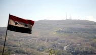 A Syrian national flag flutters as Qasioun mountain is seen in the background from Damascus, Syria. REUTERS/Omar Sanadiki