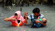 FILE PHOTO: Rohingya refugees carry their child as they walk through water after crossing border by boat through the Naf River in Teknaf, Bangladesh September 7, 2017. (Reuters / Mohammad Ponir Hossain) 