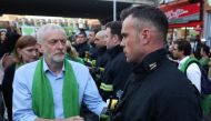 Britain's opposition Labour Party leader Jeremy Corbyn (L) shakes hands with a fire-fighter lining the street as members of the public take part in a silent march as part of commemorations on the first anniversary of the Grenfell fire in west London on Ju
