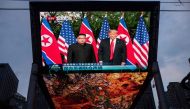 A giant TV screen shows US President Donald Trump (R) and North Korea's leader Kim Jong Un shake hands following a signing ceremony during their historic US-North Korea summit, in Beijing on June 12, 2018. AFP / Johannes EISELE