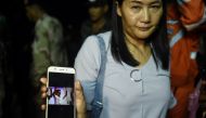 A relative shows the photograph of missing Adorn Sanorn, 14, as family members keep vigil near Tham Luang cave at the Khun Nam Nang Non Forest Park in Chiang Rai on June 26, 2018 while rescue personnel conduct operation for a missing children's football t