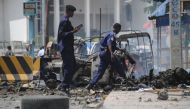 Somali security force personnel walk near the wreckage of burnt-out vehicles at the site of a car bomb explosion near the building of the Interior Ministry in Mogadishu on July 7, 2018. AFP / Mohamed Abdiwahab 