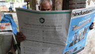 This photo illustration shows an Indian newspaper vendor reading a newspaper with a full back page advertisement from WhatsApp intended to counter fake information, in New Delhi on July 10, 2018.  AFP / Prakash Singh