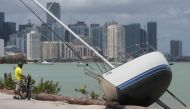 A man looks at a boat that has come ashore with the city of Miami in the background following Hurricane Irma in Key Biscayne, Florida, U.S., September 11, 2017. Reuters/Carlo Allegri