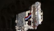 The Syrian national flag rises in the midst of damaged buildings in Daraa-al-Balad, an opposition-held part of the southern city of Daraa, on July 12, 2018. Syria's army entered rebel-held parts of Daraa city , state media said, raising the national flag 