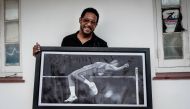 Cuban former high jumper Javier Sotomayor poses with a picture of himself in Havana, on June 20, 2018. (AFP / ADALBERTO ROQUE)