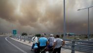 People look at smoke as a wildfire burns in Kineta, near Athens, Greece, July 23, 2018. Reuters/Alkis Konstantinidis
