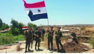 A handout picture released by the official Syrian Arab News Agency (SANA) on July 26, 2018 shows Syrian army soldiers carrying the national flag in the village of Hamidiya in the southern province of Quneitra.  AFP /SANA