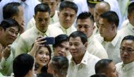 Philippine President Rodrigo Duterte poses for a selfie while surrounded by supporters and lawmakers after delivering his state of the nation address at Congress in Manila on July 23, 2018. / AFP / Noel Celis