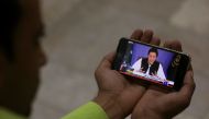 A journalist poses with a cell phone displaying Imran Khan, Prime Minister of Pakistan, speaking to the nation in his first televised address, in Karachi, Pakistan August 19, 2018. (REUTERS/Akhtar Soomro)