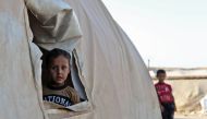 A young boy peeks out of a tent in a camp for the displaced from Idlib's southern province and Hama's northern provice, in Kafr Dariyan situated at a short distance from Syria's border with Turkey, on August 26, 2018. / AFP / OMAR HAJ KADOUR
