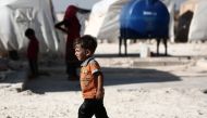 A child walks in front of tents at a camp for the displaced from the rebel-held Syrian province of Idlib, at the village of al-Ghadfa, southeast of the province on September 2, 2018. AFP / Nazeer AL-KHATIB
