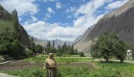 A resident of Siksa, Pakistan, stands near crops irrigated with water from a new pipeline and storage tank system serving the village, September 4, 2018. Thomson Reuters Foundation/Rina Saeed Khan