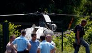 In this file photo taken on July 1, 2018 in Gonesse, north of Paris police patrol near a French helicopter Alouette II abandoned by French armed robber Redoine Faid after his escape from prison in Reau. / AFP / GEOFFROY VAN DER HASSELT
