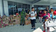 Passengers boarding a commercial flight walk past packages of aid at the Mutiara Sis Al Jufri airport in Palu on October 10, 2018, days after the airport reopened following the September 28 earthquake and tsunami.  AFP / Adek Berry

