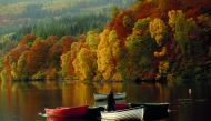 A man stands on a boat as autumn foliage is reflected off Loch Faskally, in Perthshire, Scotland, Britain, October 19, 2018. Reuters/Russell Cheyne
