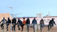 FILE PHOTO: Migrants sit atop a border fence separating Morocco from the north African Spanish enclave of Melilla in the first attempt to jump since the camp on Mount Gurugu burned down.   AFP / ANGELA RIOS
