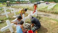 A family a tombstone of a relative at a mass grave for victims of Super Typhoon Haiyan during the fifth anniversary of the typhoon in Tacloban City, Leyte province, central Philippines on November 8, 2018.  AFP