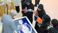 A staff of WCM-Q explains to students about various parts of human body at an anatomage table during the event. 