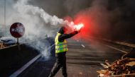 A man burn a flare as people block Caen's circular road on November 18, 2018 in Caen, Normandy, on a second day of action, a day after a nationwide popular initiated day of protest called 