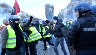A Yellow vest (Gilet jaune) demonstrator gestures next to a gendarme on the Champs Elysees in Paris, on November 24, 2018, during a protest against rising oil prices and living costs. AFP / Bertrand Guay