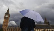 A woman looks towards dark clouds over the Houses of Parliament in central London, August 11, 2014. Reuters/Luke MacGregor