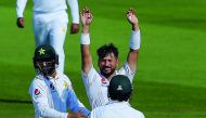 Pakistani spinner Yasir Shah (C) celebrates with teammates after breaking the fastest to 200 Test wickets record during the fourth day of the third and final Test cricket match between Pakistan and New Zealand at the Sheikh Zayed International Cricket Sta