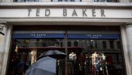 People shelter under umbrellas as they pass a Ted Baker a store in London, Britain October 06, 2015. Reuters/Neil Hall
 