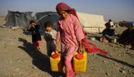 In this photo taken on August 3, 2018, a drought-displaced Afghan girl carries water containers filled from a tanker at a camp for internally displaced people in Injil district of Herat province. AFP / Hoshang Hashimi 