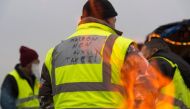 A protester wearing a yellow vest (gilet jaune) with a message reading 