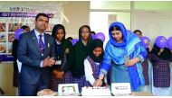 School officials with Sudanese students cutting a cake.