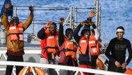 Migrants, part of a group of 49, wave towards the media as they disembark from one of Malta's AFM Protector-class coastal patrol boats on January 9, 2019 after being transfered from the Dutch-flagged rescue Vessel 