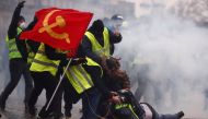Protesters wearing yellow vests help a person injured by a water cannon during a demonstration by the 